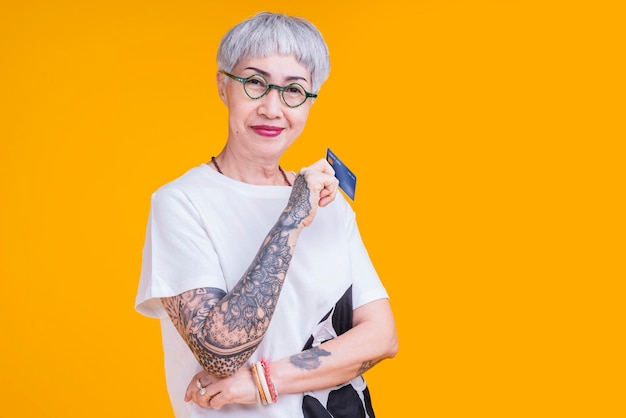 Old senior asian woman tattoo hand show credit card with smile confident and cheerful studio shotasia old woman grey hair standing hand gesture hold credit care cashless payment business ideas