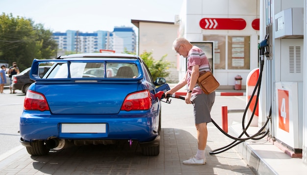 The old senior man refill his car with gasoline on the fuel station, tourist traveling