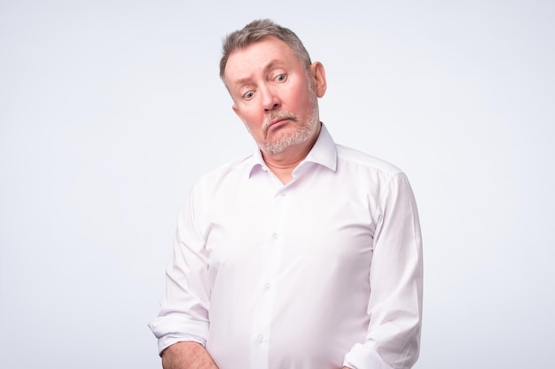 Old senior man in white shirt with serious and sad expression