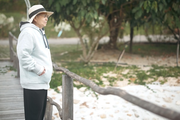 old senior woman walking relaxing on bridge in park