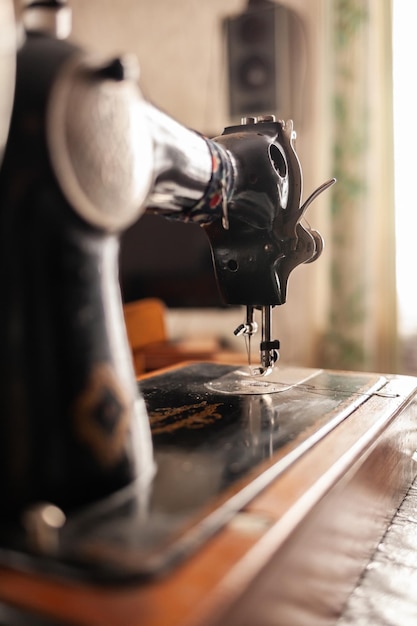 An old sewing machine stands on the table at home ready to work and sew Classic retro style