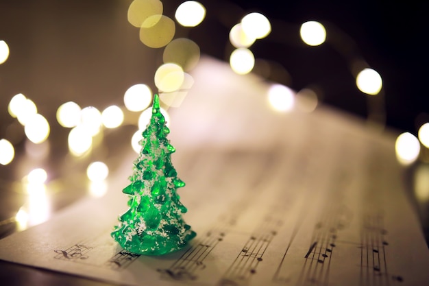 Old sheet with Christmas music notes as background against blurred lights. Christmas music concept