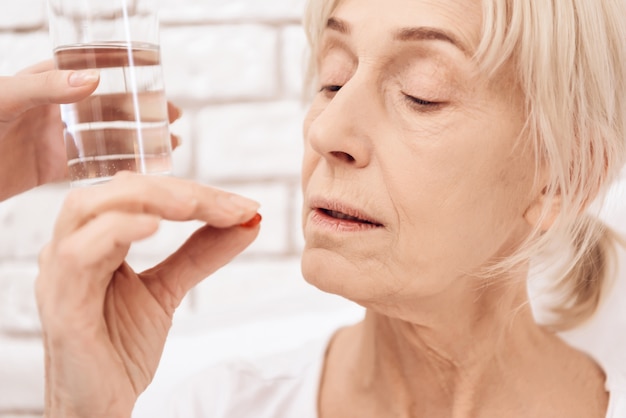 Old sick woman drinking pills