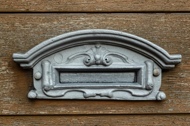 Old silver metal mailbox on a shabby wooden door somewhere