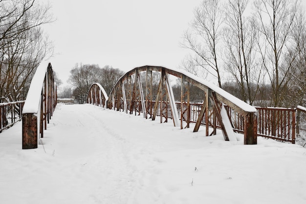 Old steel road bridge over  river  after snowfall