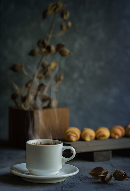 Old style still life with croissants and a hot cup of coffee