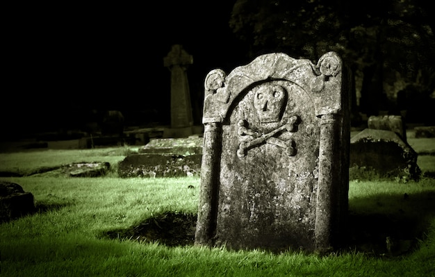 Old tombstone with skull and bones in a graveyard