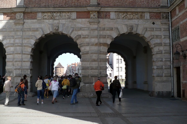 Old town square buildings lit by the sun in a row people in the market square Gdansk Poland three archways