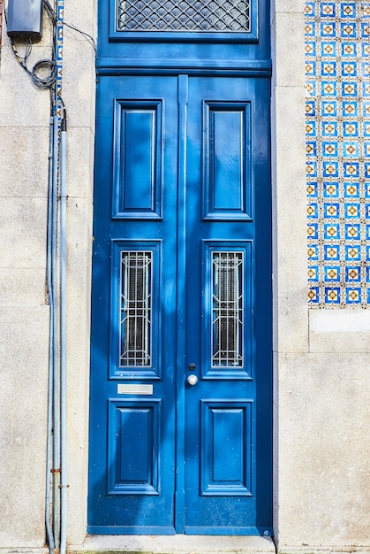 Old traditional wooden door with wrought iron door knockers on white facade in portugal