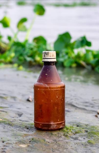 Old used empty insecticide bottle near the river close up