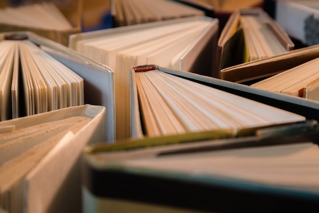 Old and used hardback books, text books seen from above on wooden floor.