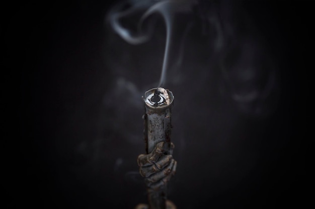 Old vintage black metal candlestick with smoke from an extinguished candle in the dark Witchcraft and Religion Closeup Black background