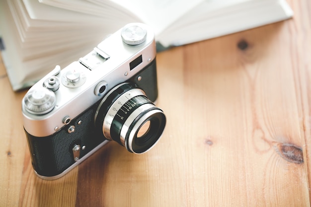 Old vintage camera with book on a wooden table