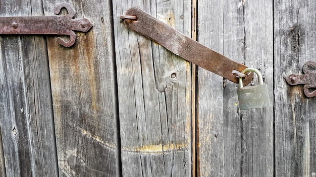 Old vintage metal padlock on a closed wooden door of an old farmhouse. The true style of the village. close-up. focus on the castle. Wooden background, texture. Copy space.