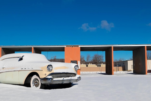 Old vintage retro car covered and sorrounded by snow under blue sky