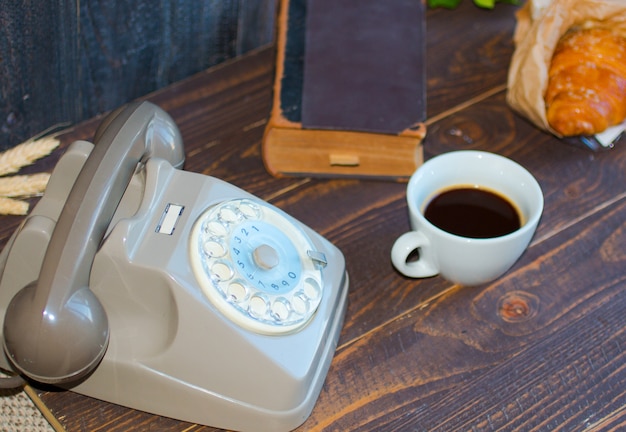 Old vintage telephone, coffee, book, on a wooden background,