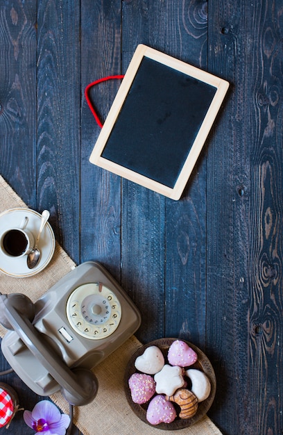 Old vintage telephone, with biscotti, coffee, donuts on a wooden background