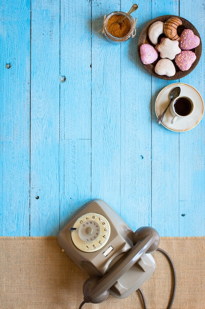 Old vintage telephone, with biscotti, coffee, donuts on a wooden background