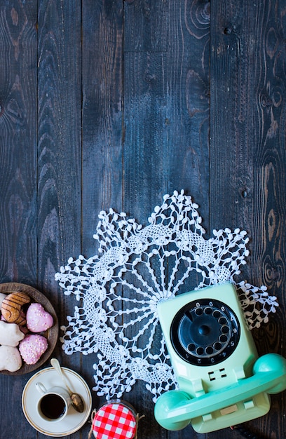 Old vintage telephone, with biscotti, donuts on a wooden background, free space for text