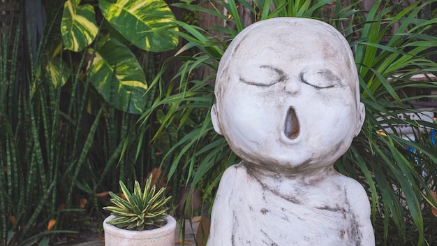 The old vintage white stucco little monk garden ornamental doll in praying gesture in home garden