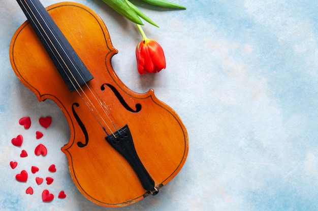 Old violin, red heart figurines and red tulip. 