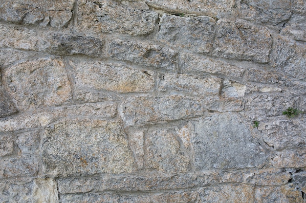 Old wall made of big stones and broken bricks. Vintage rough blocks surface background