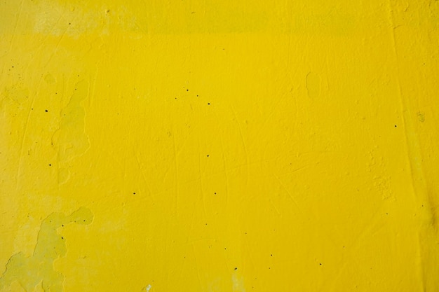 Old wall painted with yellow paint with cracks and bubbles