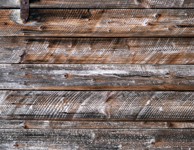 Old weathered wooden wall with horizontal boards and rusty nails in it