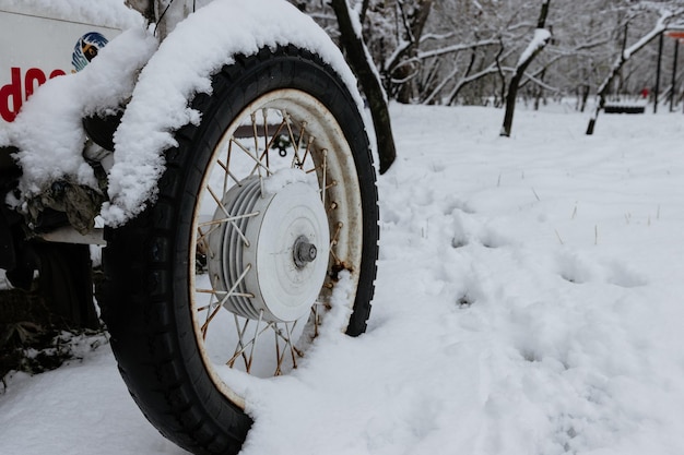 Old wheel with spokes in the snow Close up vintage white car wheel over snow cover in winter time