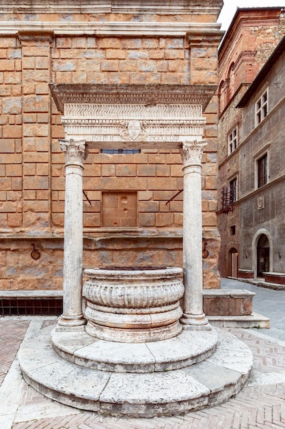 Old white marble fountain Piccolomini well in Piazza Pio II in Pienza