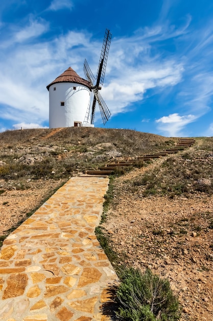 Old white windmills, made of stone, on the field with blue sky and white clouds. La Mancha, Castilla, Spain. Europe,