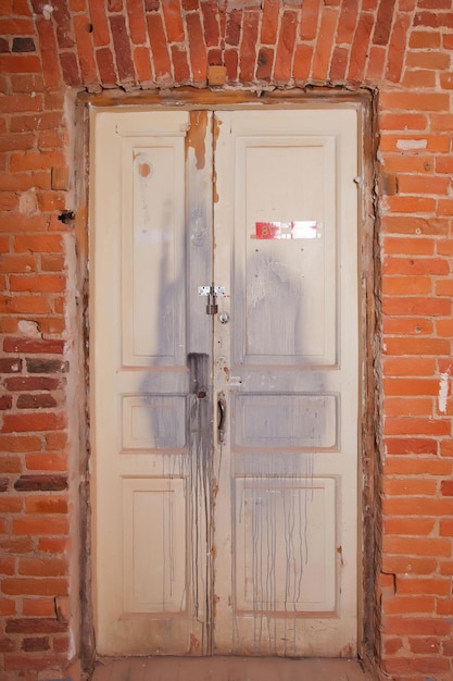 Old white wooden door with brick red old wall