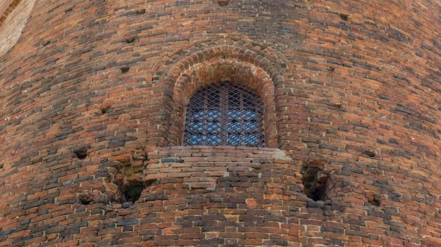 Old window in the castle window with bars in an old brick wall