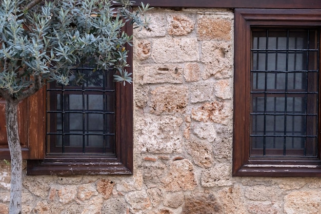 Old windows with wooden frames and bars on an ancient stone building