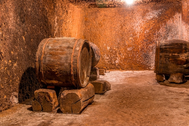 Old wine cellar with textured walls. Large oak barrels on the stone coasters