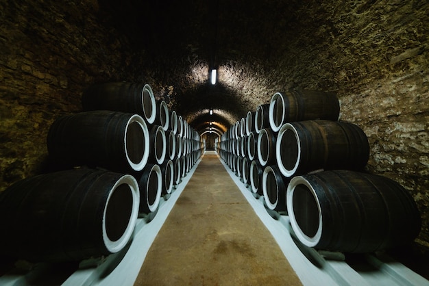 Old wine oak barrels in a wine cellar stored in a winery