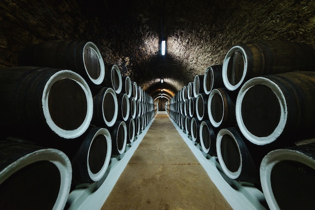 Old wine oak barrels in a wine cellar stored in a winery