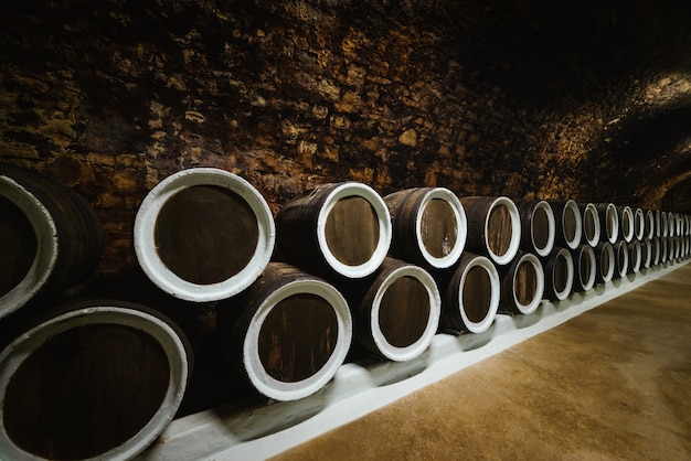 Old wine oak barrels in a wine cellar stored in a winery