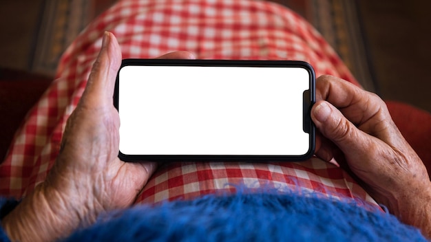 Old woman at home using a mobile phone with white screen Mockup device