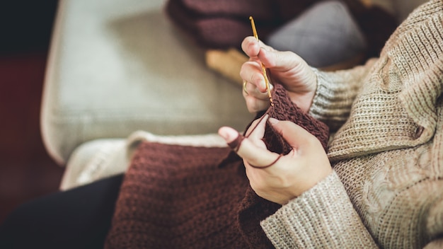 Old woman knitting a brown scarf