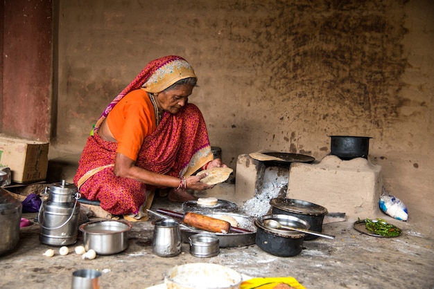 Old woman making and cooking baking fresh food in a rural village in a vintage kitchen