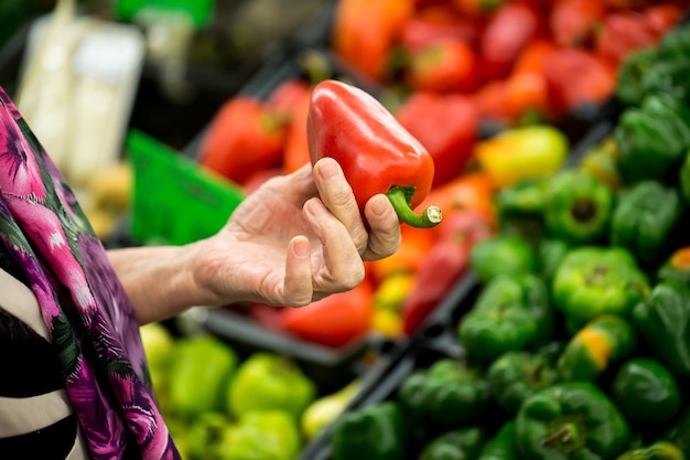 Old woman picking pepper at the supermarket