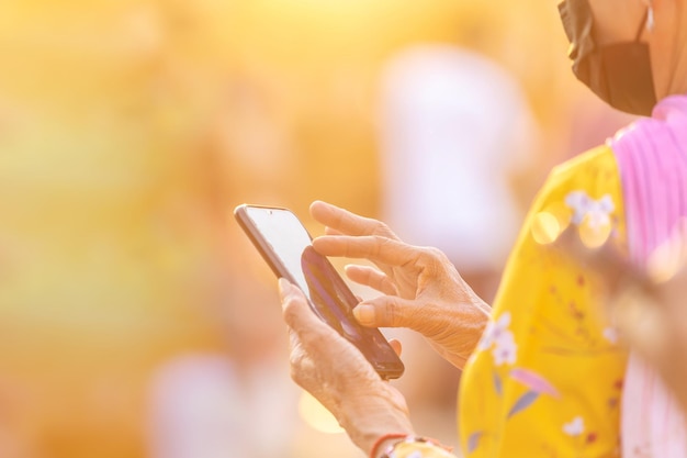 Old woman's hand using smartphone at outdoor in evening time