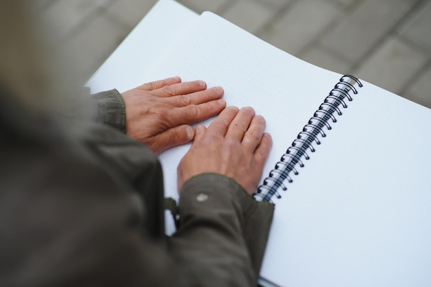 Old woman' s hands reading a book with braille language