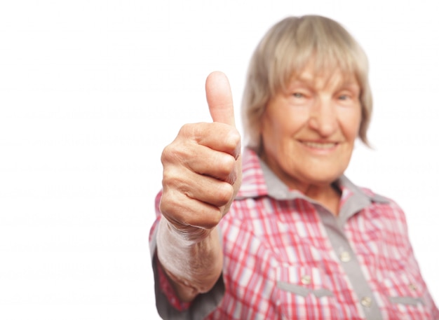 Old woman showing ok sign on a white wall