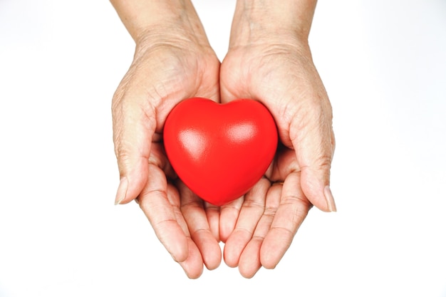 The old womans hand holding a red heart in donate help give love warmth take care. World Health Day.