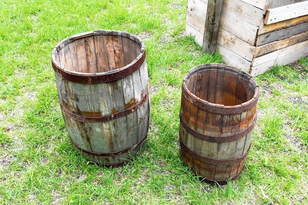 Old wooden barrels stand on the grass in the backyard in the village Texture of weathered wood