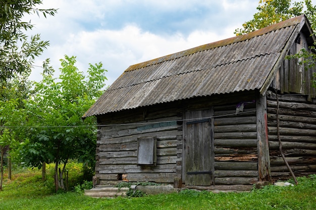 An old wooden bathhouse, a house on a green lawn.