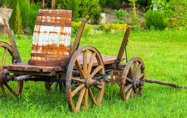 Old wooden cart with a keg on the green grass. Selective focus