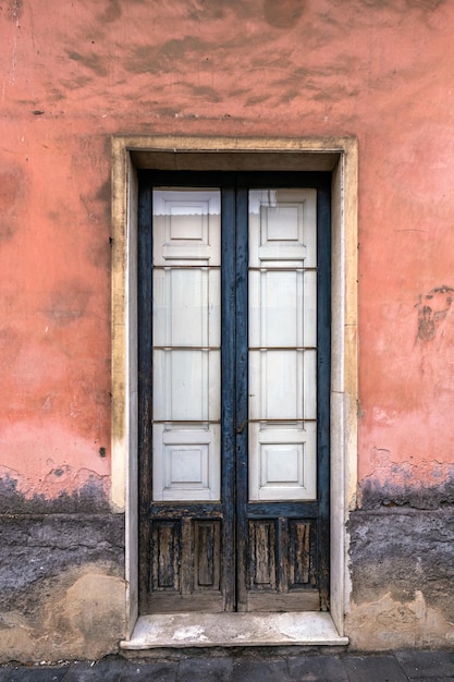 Old wooden entrance door on facade of antique baroque building in traditional architecture of Catania Sicily, Italy.